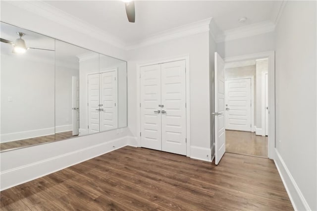 unfurnished bedroom with a ceiling fan, dark wood-type flooring, crown molding, and baseboards