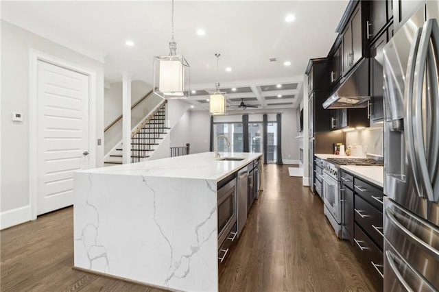 kitchen with a sink, recessed lighting, appliances with stainless steel finishes, coffered ceiling, and a kitchen island with sink