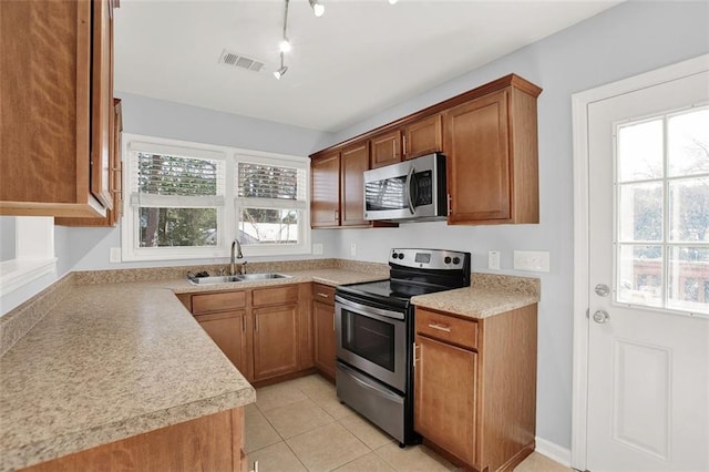 kitchen featuring sink, light tile patterned flooring, track lighting, and stainless steel appliances