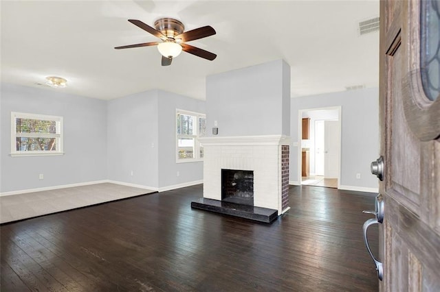 unfurnished living room with ceiling fan, a brick fireplace, and dark hardwood / wood-style flooring