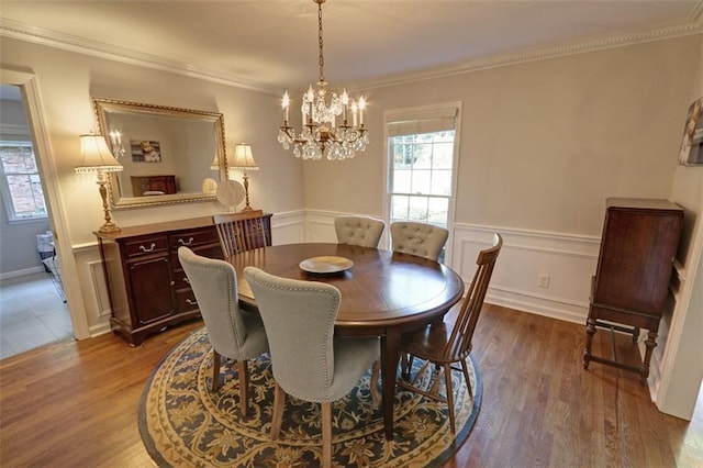 dining space with dark hardwood / wood-style flooring, ornamental molding, and a chandelier