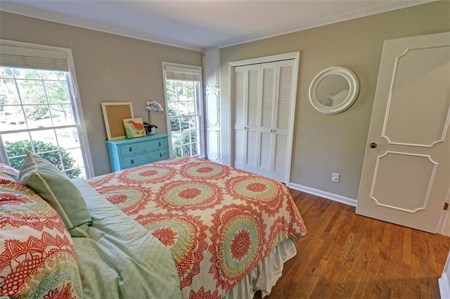 bedroom with a closet, dark wood-type flooring, and ornamental molding