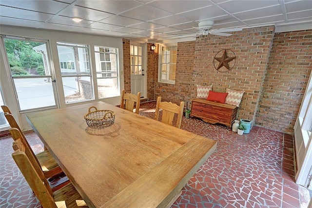 dining room featuring a paneled ceiling, brick wall, and ceiling fan