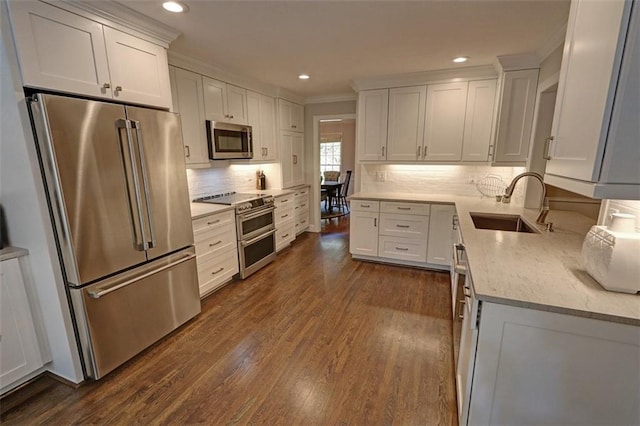 kitchen featuring white cabinets, dark hardwood / wood-style floors, premium appliances, backsplash, and sink