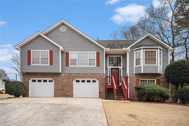 bi-level home featuring an attached garage, concrete driveway, and brick siding