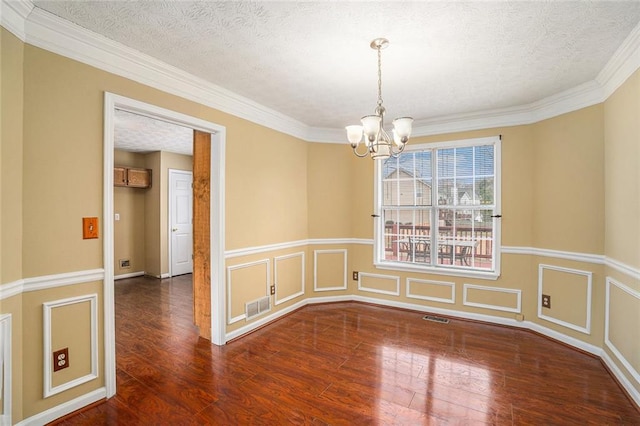 spare room featuring a chandelier, visible vents, a textured ceiling, and wood finished floors