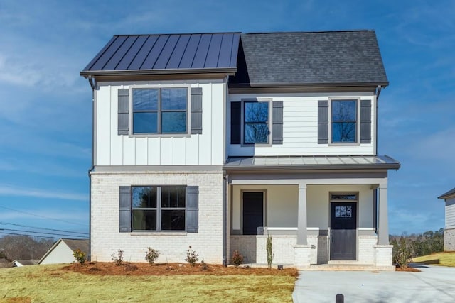 view of front facade featuring brick siding, board and batten siding, covered porch, metal roof, and a standing seam roof