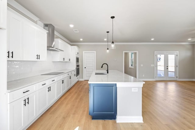 kitchen featuring a sink, white cabinets, wall chimney range hood, black electric cooktop, and backsplash