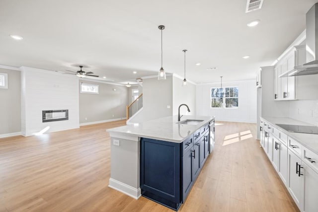 kitchen with visible vents, black electric stovetop, a fireplace, a sink, and wall chimney range hood