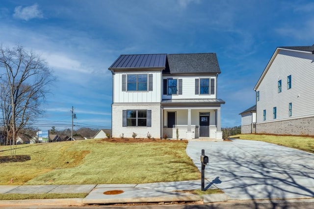 view of front of home featuring a standing seam roof, a porch, a front lawn, board and batten siding, and brick siding