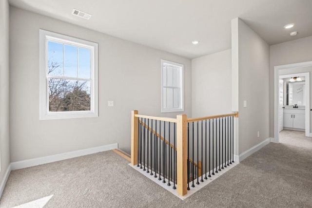 corridor with visible vents, baseboards, carpet floors, an upstairs landing, and recessed lighting