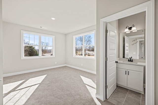 unfurnished bedroom featuring light carpet, baseboards, and a sink