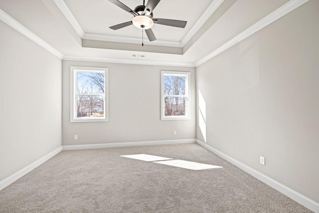 carpeted empty room with baseboards, a raised ceiling, visible vents, and ornamental molding