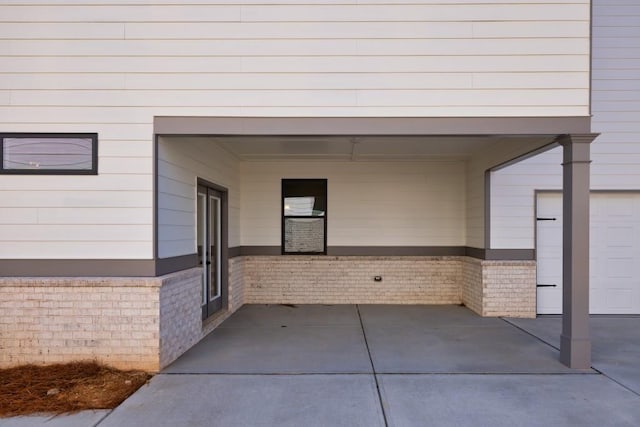 entrance to property with brick siding, driveway, and a carport