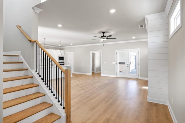 stairs with wood finished floors, french doors, crown molding, baseboards, and ceiling fan