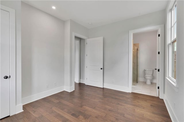 unfurnished bedroom with dark wood-type flooring and connected bathroom