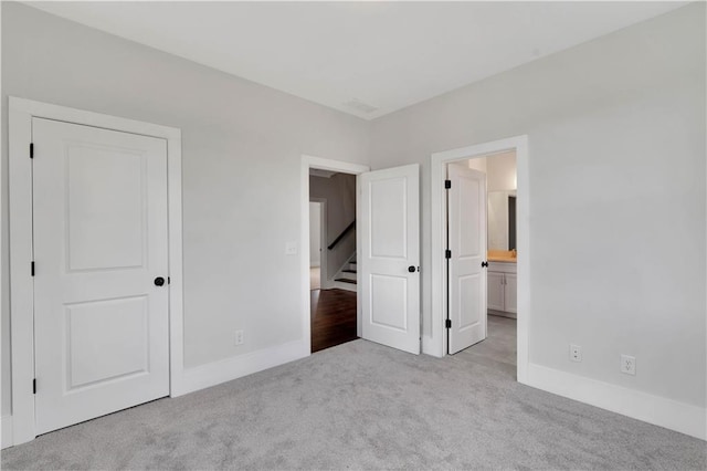 unfurnished bedroom featuring light carpet and ensuite bath