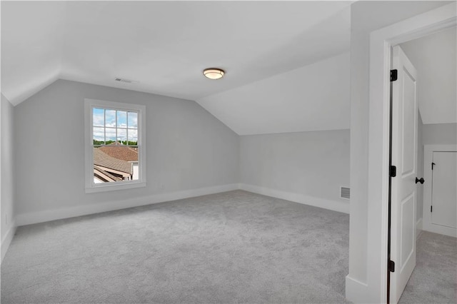 additional living space with light colored carpet and vaulted ceiling