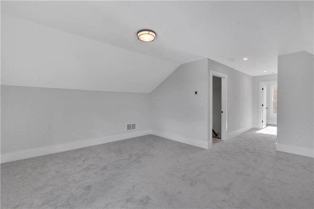 bonus room with vaulted ceiling and light colored carpet