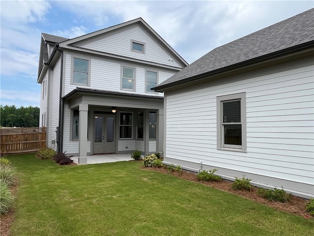 back of property with french doors, a lawn, and a patio