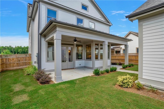rear view of property featuring ceiling fan, a patio area, and a yard