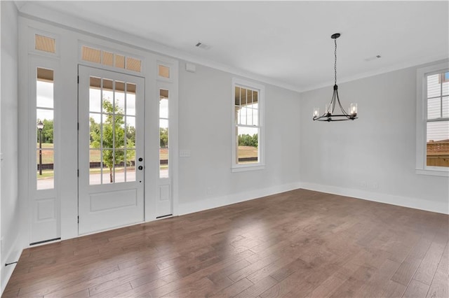 interior space featuring dark hardwood / wood-style floors, ornamental molding, a chandelier, and a healthy amount of sunlight