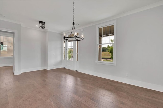 unfurnished dining area featuring dark wood-type flooring, an inviting chandelier, and ornamental molding