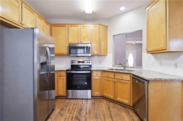 kitchen featuring light stone countertops, sink, stainless steel appliances, and light wood-type flooring