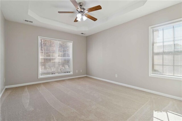 unfurnished room featuring a tray ceiling, ceiling fan, and light colored carpet