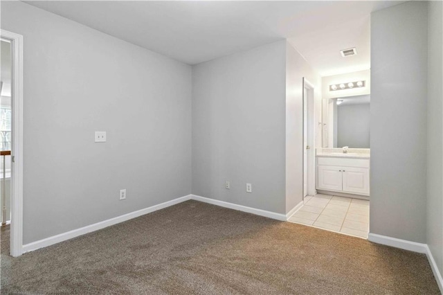 unfurnished bedroom with light carpet, ensuite bathroom, and sink