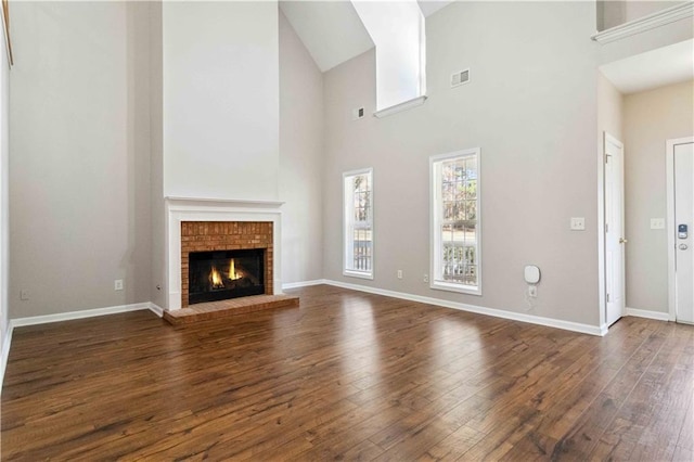 unfurnished living room featuring dark hardwood / wood-style flooring, a towering ceiling, and a fireplace