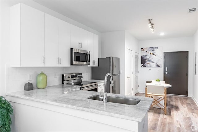 525 Parkway Dr NE Unit 306, Atlanta, GA 30308 - kitchen featuring stainless steel appliances, light wood finished floors, light stone countertops, backsplash, and white cabinets