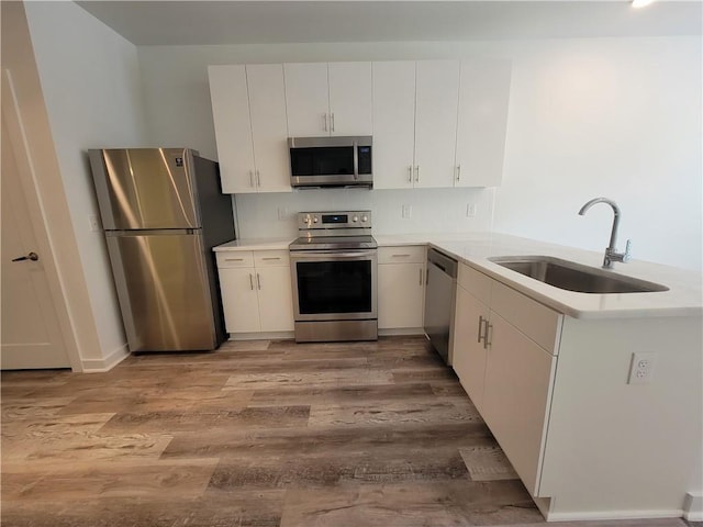 525 Parkway Dr NE Unit 306, Atlanta, GA 30308 - kitchen featuring appliances with stainless steel finishes, wood finished floors, light countertops, a peninsula, and white cabinetry