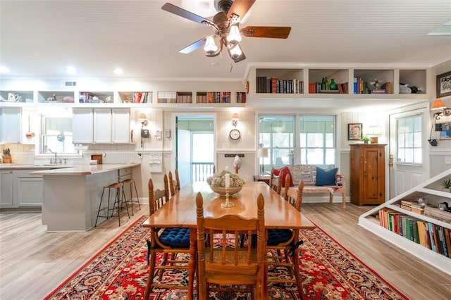 dining space with light hardwood / wood-style flooring, ceiling fan, and sink