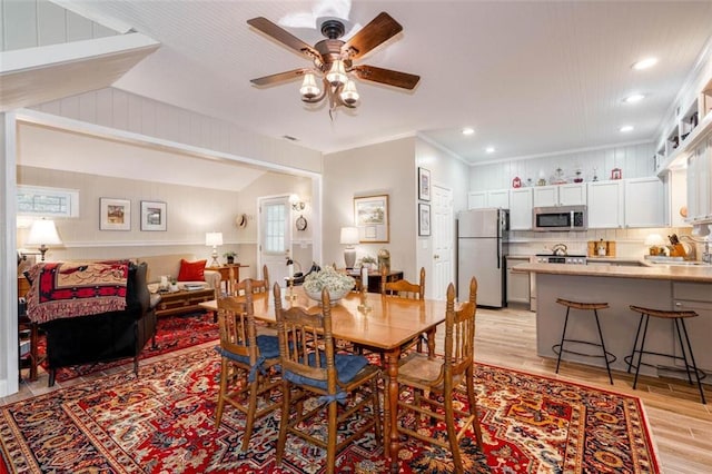 dining area featuring ceiling fan, lofted ceiling, sink, crown molding, and light hardwood / wood-style floors