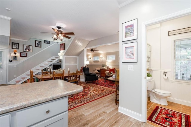 kitchen with ceiling fan, gray cabinets, light wood-type flooring, and crown molding