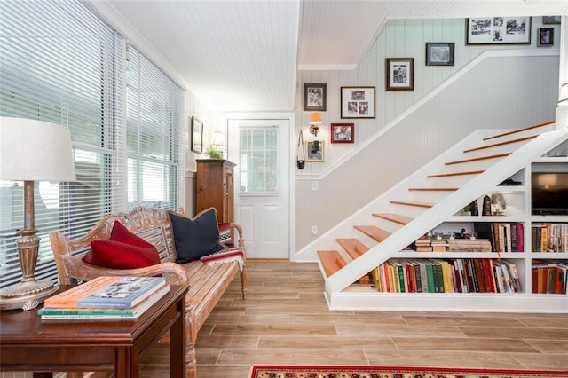 living room featuring ornamental molding, wooden walls, and hardwood / wood-style floors