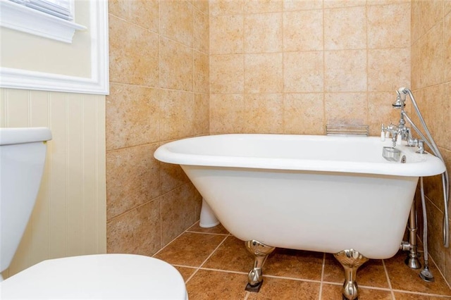 bathroom with a bathtub, tile walls, toilet, and tile patterned floors