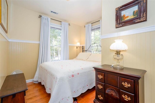 bedroom featuring wooden walls and light hardwood / wood-style floors