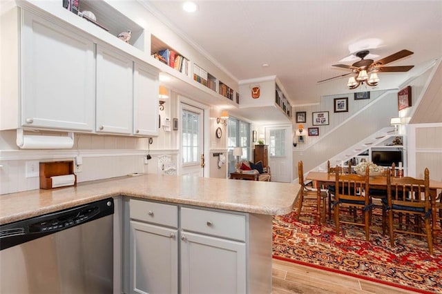 kitchen with ceiling fan, ornamental molding, kitchen peninsula, stainless steel dishwasher, and light wood-type flooring