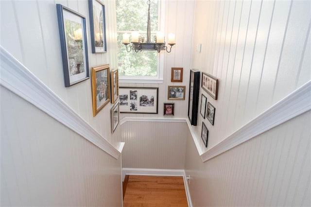 stairway with hardwood / wood-style floors and a chandelier