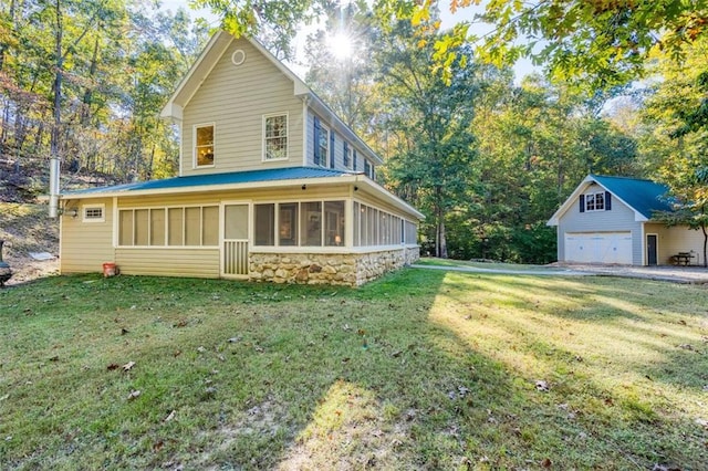 exterior space with a garage, an outdoor structure, a front lawn, and a sunroom