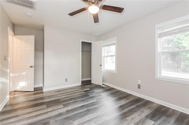 unfurnished bedroom featuring a ceiling fan, baseboards, wood finished floors, visible vents, and a closet