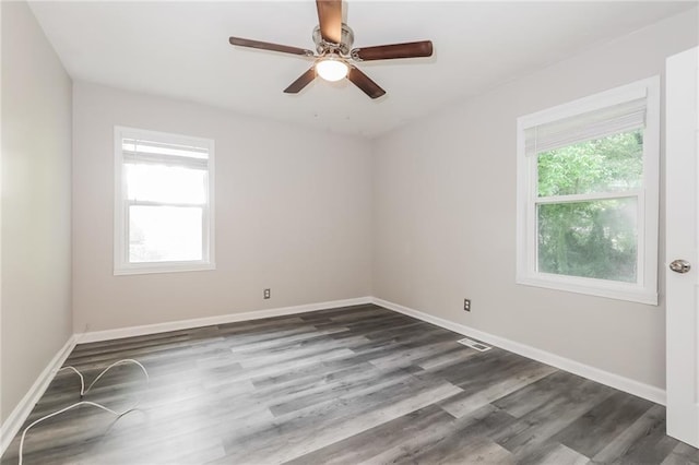 unfurnished room with baseboards, dark wood-style flooring, ceiling fan, and visible vents