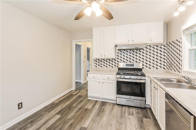 kitchen with a ceiling fan, appliances with stainless steel finishes, a sink, light countertops, and extractor fan