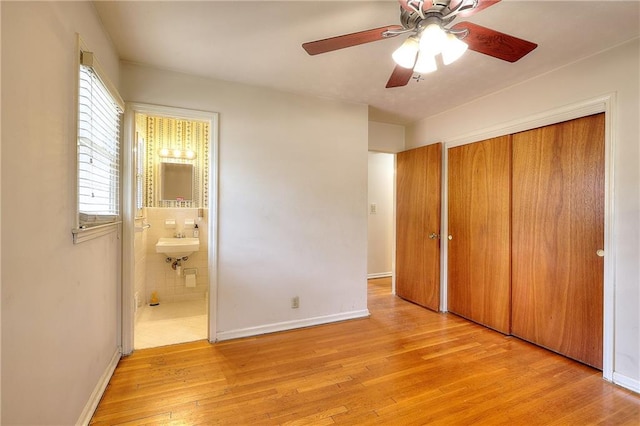 unfurnished bedroom with connected bathroom, sink, a closet, ceiling fan, and light hardwood / wood-style floors