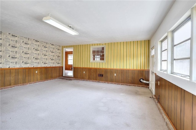 carpeted empty room featuring wooden walls