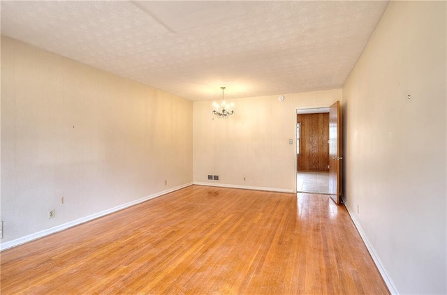 empty room with light hardwood / wood-style floors and a notable chandelier