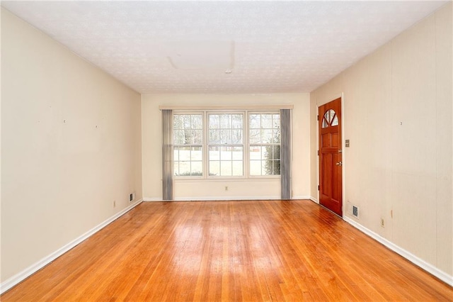 unfurnished room featuring a textured ceiling and light hardwood / wood-style flooring