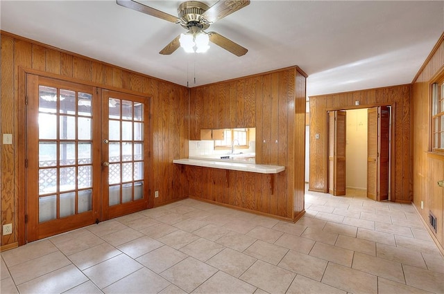 kitchen featuring sink, ceiling fan, wooden walls, french doors, and kitchen peninsula